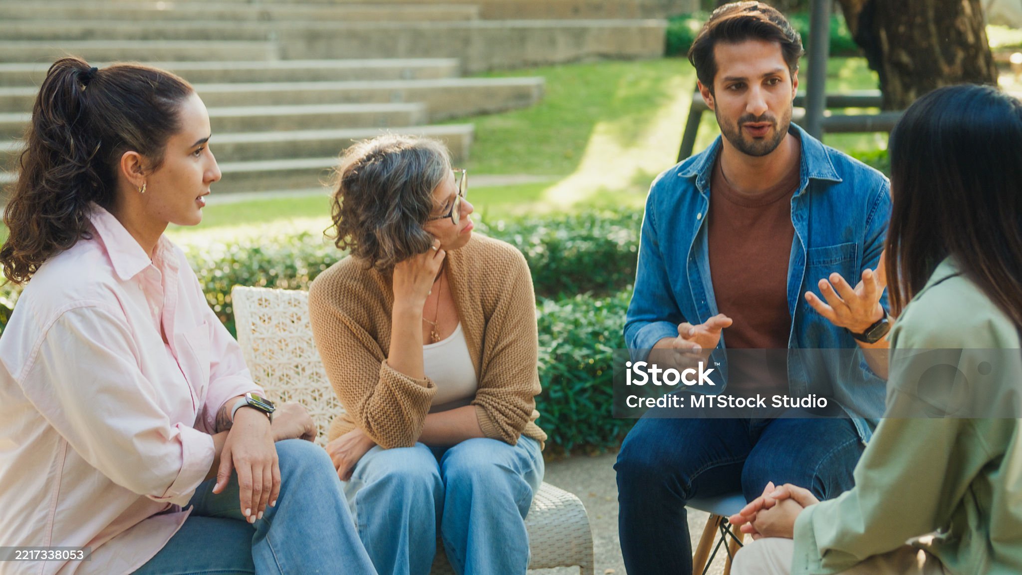 A group of young adults in open conversation outdoors